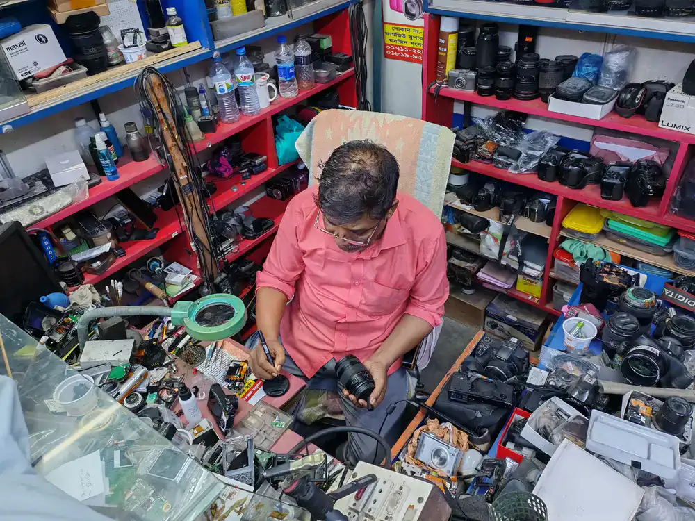A technician carefully repairing a camera lens on a clean workbench